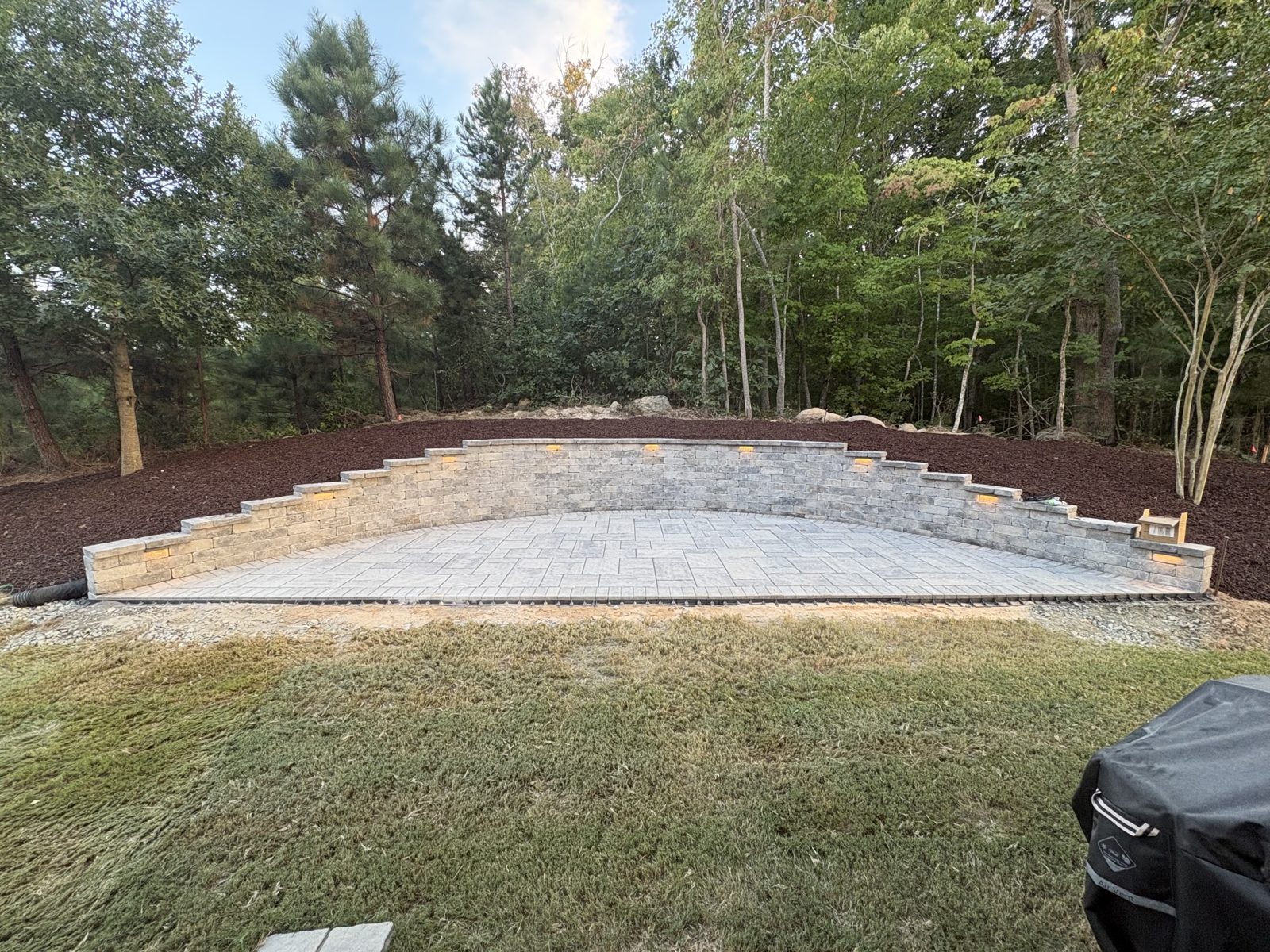 Tiered stone terrace and paver patio lit up at dusk