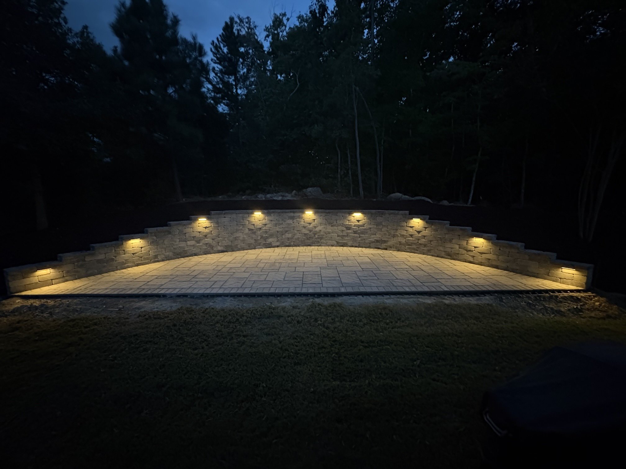 Low voltage lighting built into the steps of a stone terrace, glowing after dark